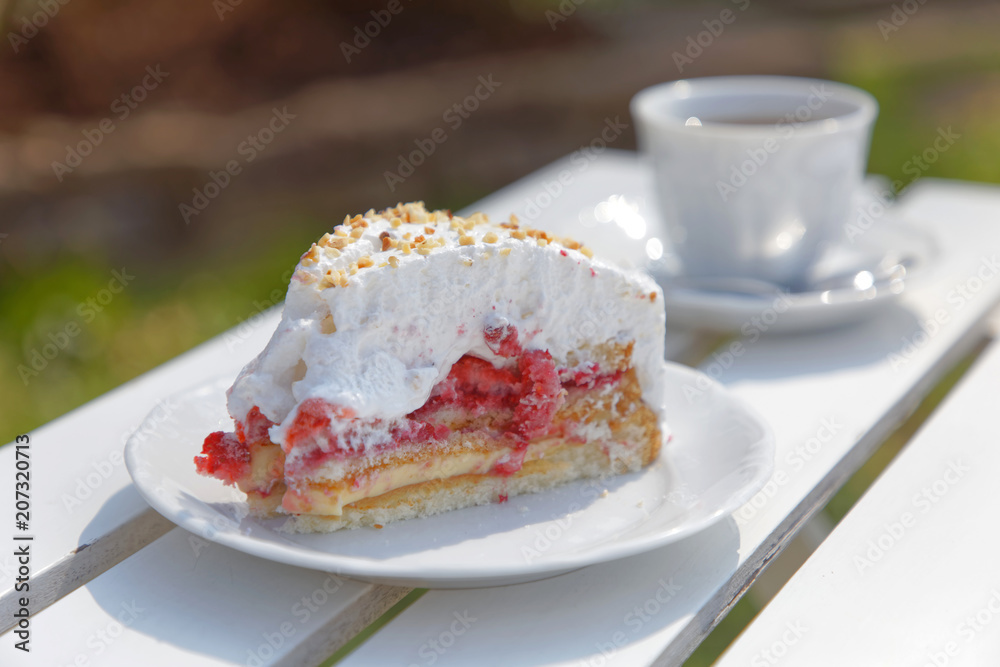 Cup of coffe and a cake made of raspberry and cream on an outdoor table at Borgholm on the island Oland, Sweden Cup of coffe and a cake made of raspberry and cream on an outdoor table at Borgholm on the island Oland, Sweden