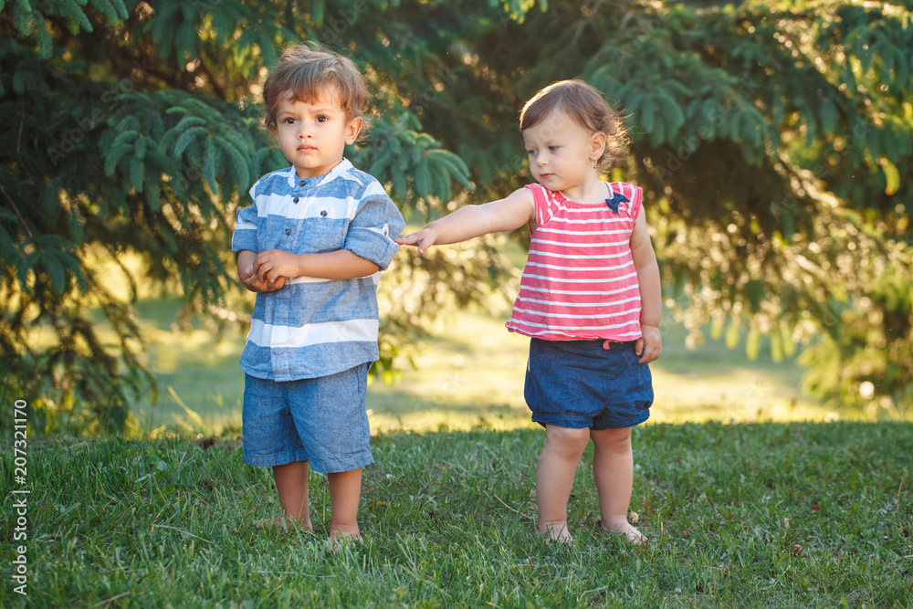 Group portrait of two white Caucasian cute adorable funny boy and girl toddlers in park outside in summer. Children quarrel and reconciliation. Love friendship childhood concept. Best friends forever ...