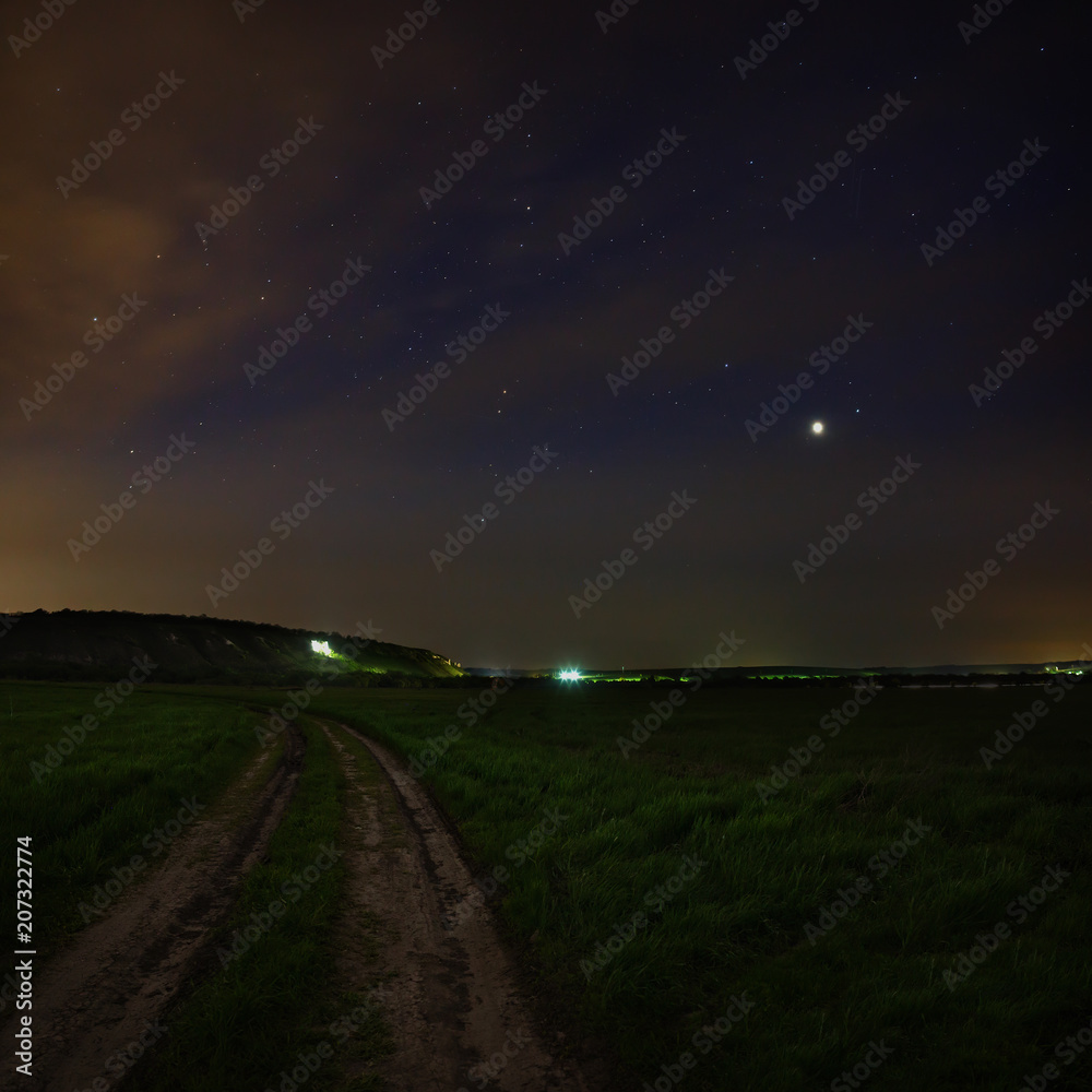 Jupiter in the night sky with the stars. Rural road at dusk. Cosmic space above the earth's surface. Long exposure.