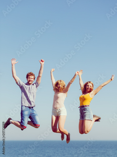 Group of friends boy two girls jumping outdoor