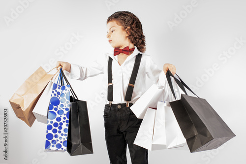 Impressive look boy with shopping. Gray background.