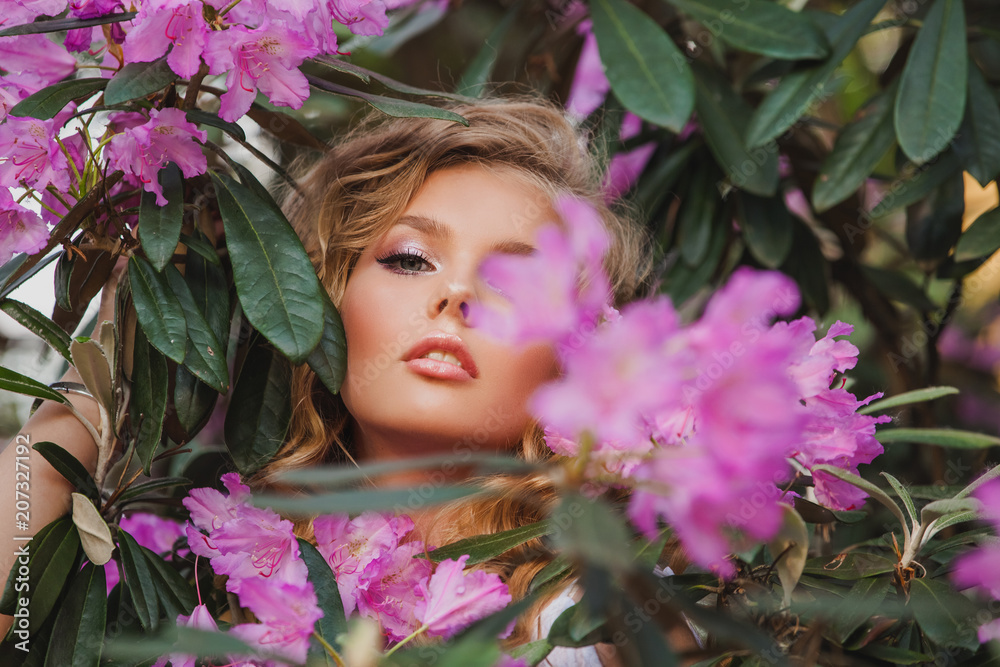 Portrait of a girl in a blooming garden. A bush of flowers is rhododendron pink. Beautiful hair and makeup. Portrait of a girl in a blooming garden. A bush of flowers is rhododendron pink. Beautiful hair and makeup.
