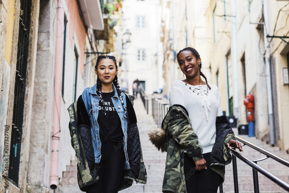 Portugal, Lisbon, Two smiling young women walking outdoors Portugal, Lisbon, Two smiling young women walking outdoors