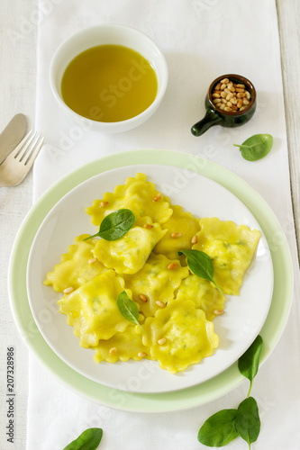 Ravioli with ricotta and spinach, served with olive oil and pine nuts. Rustic style.