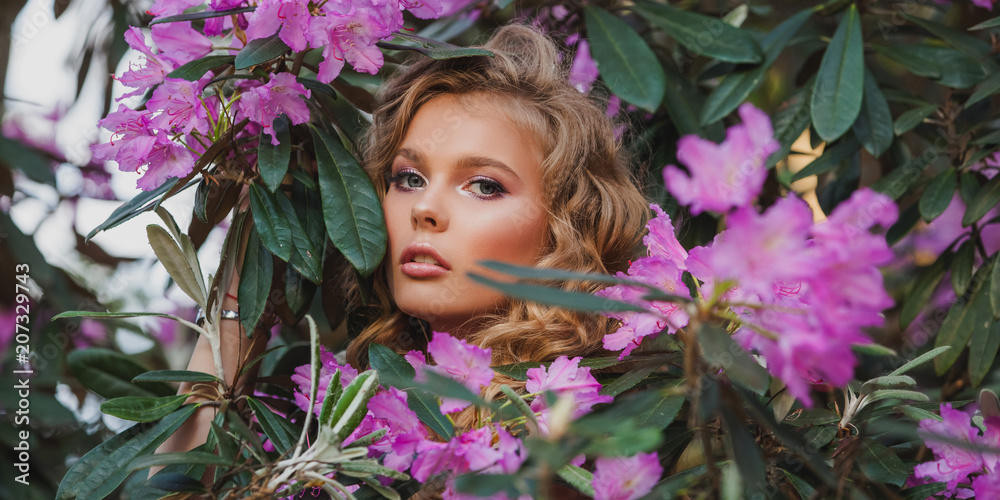 Portrait of a girl in a blooming garden. A bush of flowers is rhododendron pink. Beautiful hair and makeup. Portrait of a girl in a blooming garden. A bush of flowers is rhododendron pink. Beautiful hair and makeup.