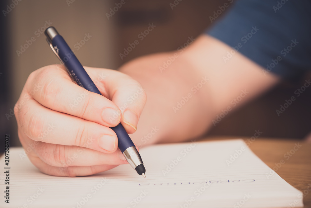 Man's hand writing on a notepad with a pen, copywriting concept Man's hand writing on a notepad with a pen, copywriting concept