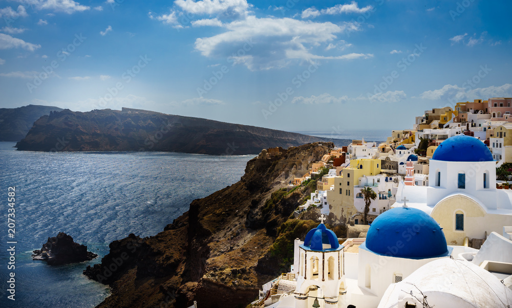 Oia town on Santorini island, Greece. Traditional and famous houses and churches with blue domes over the Caldera, Aegean sea at sunny day