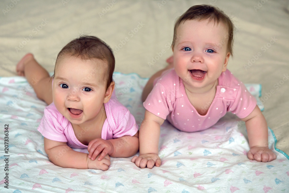two sisters twins baby in pink clothes lying on the bed two sisters twins baby in pink clothes lying on the bed