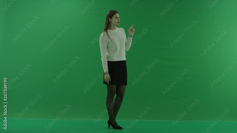 young woman stands in a half-turn, looks at the righ, scrolls the screen and considers something on green screen young woman stands in a half-turn, looks at the righ, scrolls the screen and considers something on green screen