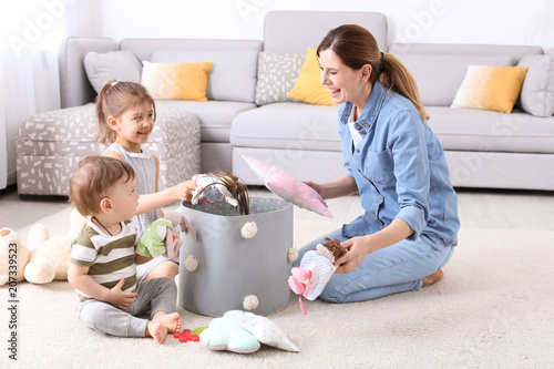 Housewife and children picking up toys after playing at home