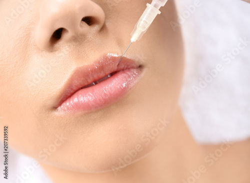 Young woman getting lip injection in beautician salon, closeup