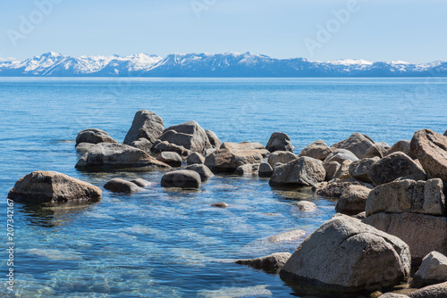 Rocks in Lake Tahoe with snow capped mountains in background.
