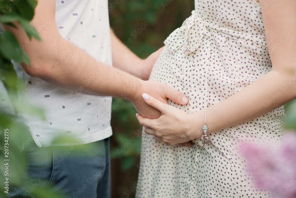 Young married couple waiting for the birth of a child. The future father touches the pregnant belly of his wife Young married couple waiting for the birth of a child. The future father touches the pregnant belly of his wife