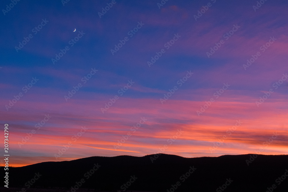 Sunset landscape with moon overlooking mountains in silhouette in Colorado's Rocky Mountain National Park. 