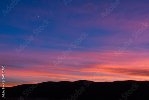 Sunset landscape with moon overlooking mountains in silhouette in Colorado's Rocky Mountain National Park. © Kristina