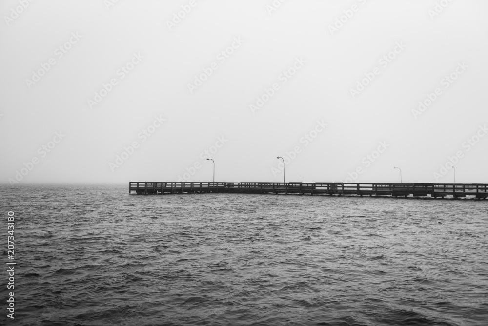 Black and white view of a dock in the Long Island, New York's Great South Bay on a cloudy morning.