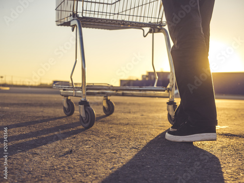 person's legs with shopping cart on the asphalt