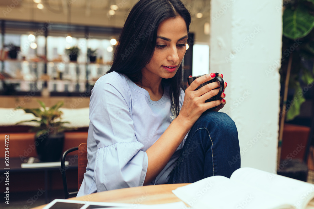 Young businesswoman reading a book while having coffee Young businesswoman reading a book while having coffee