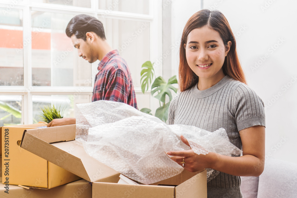 Asian married couple start new family life concept. Woman and man unpacking messy boxes after moving in new house together. Asian married couple start new family life concept. Woman and man unpacking messy boxes after moving in new house together.