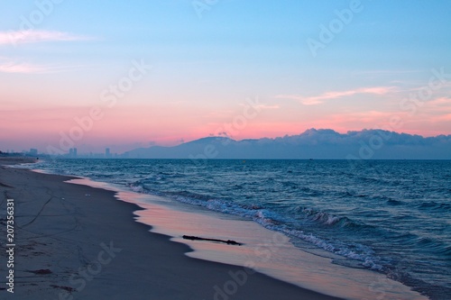 sunset seascape. blue sea and mountains. pink reflection on water surface. gradient sky