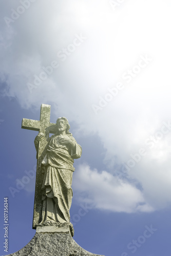 The sculpture of Jesus Christ on the background of the blue sky and white clouds