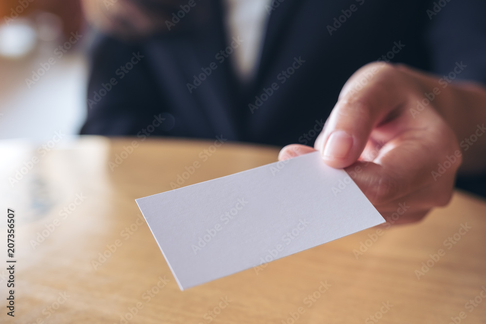 Businesswoman holding and giving an empty business card to someone on table in office Businesswoman holding and giving an empty business card to someone on table in office