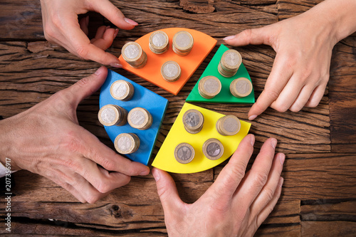 Businesspeople Stacking Coins On Pie Chart