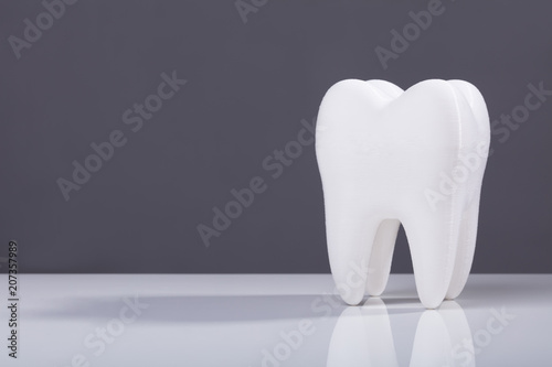 Single White Tooth On Grey Background