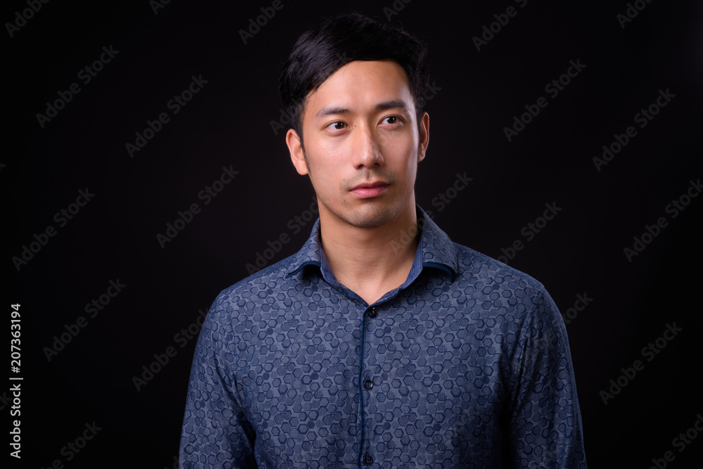 Young handsome Asian businessman against black background Young handsome Asian businessman against black background