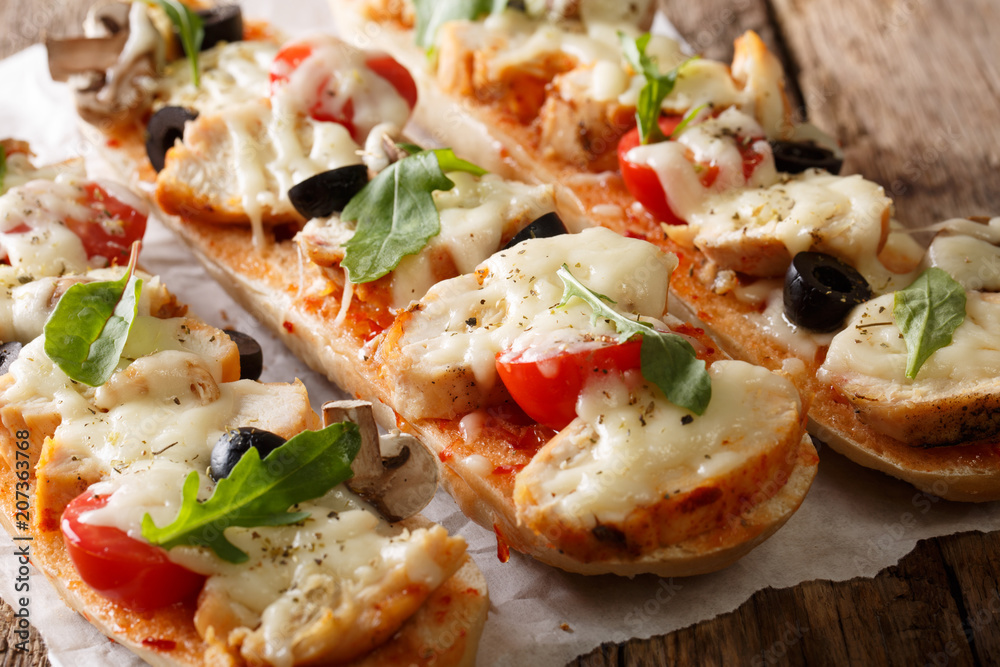 Homemade sandwich pizza baguette baked with chicken, cheese, tomatoes, olives and mushrooms close-up. horizontal