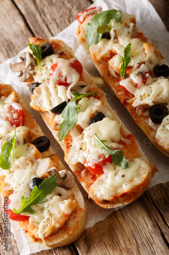 Delicious hot sandwich casserole pizza with chicken, cheese, tomatoes, olives and mushrooms close-up. vertical