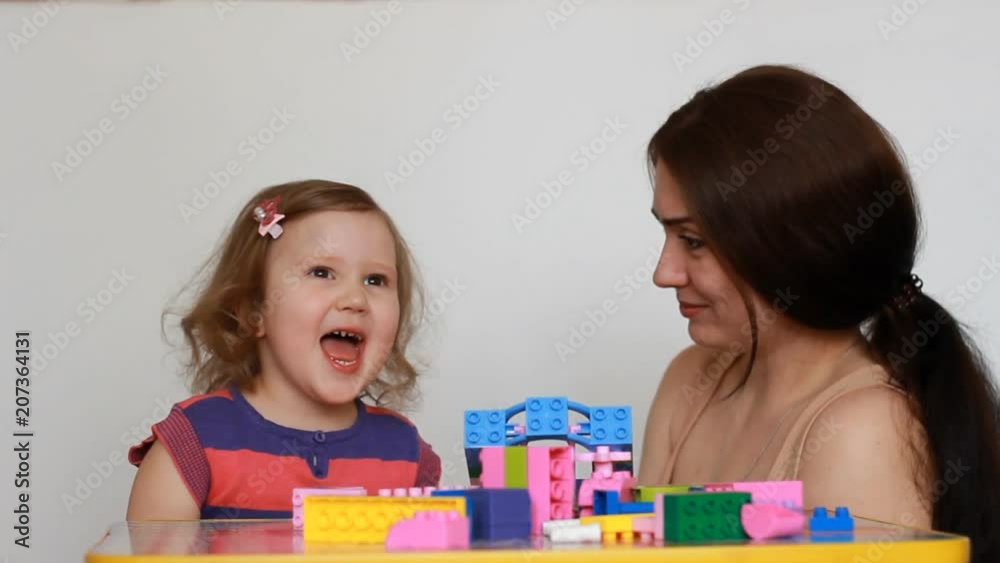 Baby girl capricious and cry, mother tries to calm the baby, Hugs and comforts. Mom and her child playing together with constructor. Baby girl capricious and cry, mother tries to calm the baby, Hugs and comforts. Mom and her child playing together with constructor.