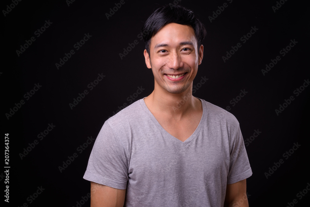 Obraz premium Young handsome Asian man against black background