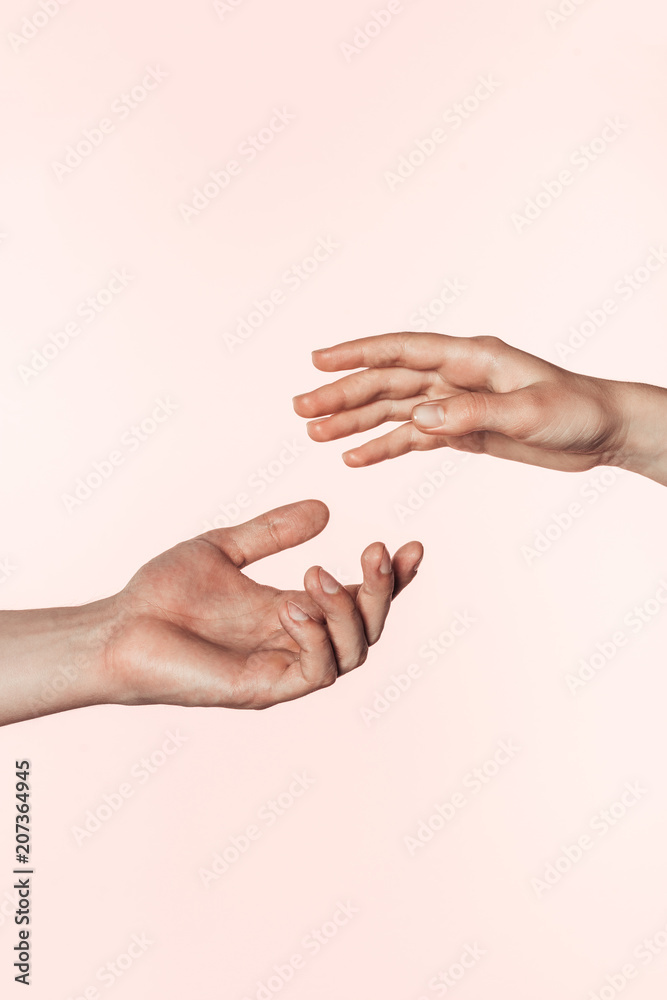 partial view of woman and man approaching hands to each other isolated on pink background