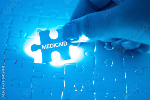 Health Care Concept. Doctor holding a jigsaw puzzle with MEDICAID word. photo