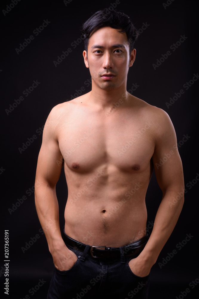Young handsome Asian man shirtless against black background Young handsome Asian man shirtless against black background