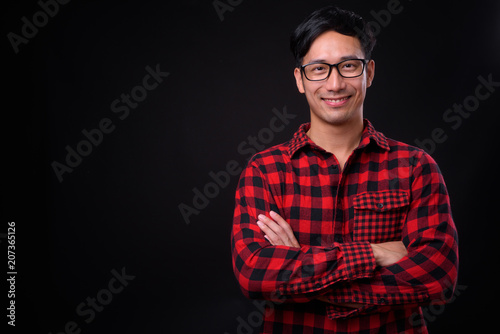 Young handsome Asian man against black background