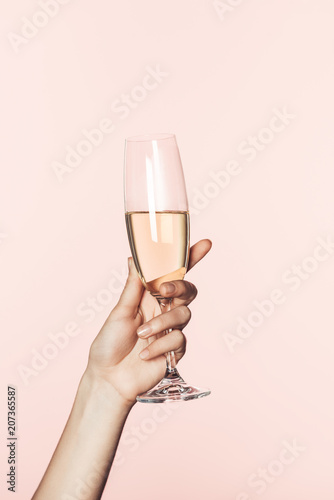 cropped shot of woman cheering by champagne glass isolated on pink background