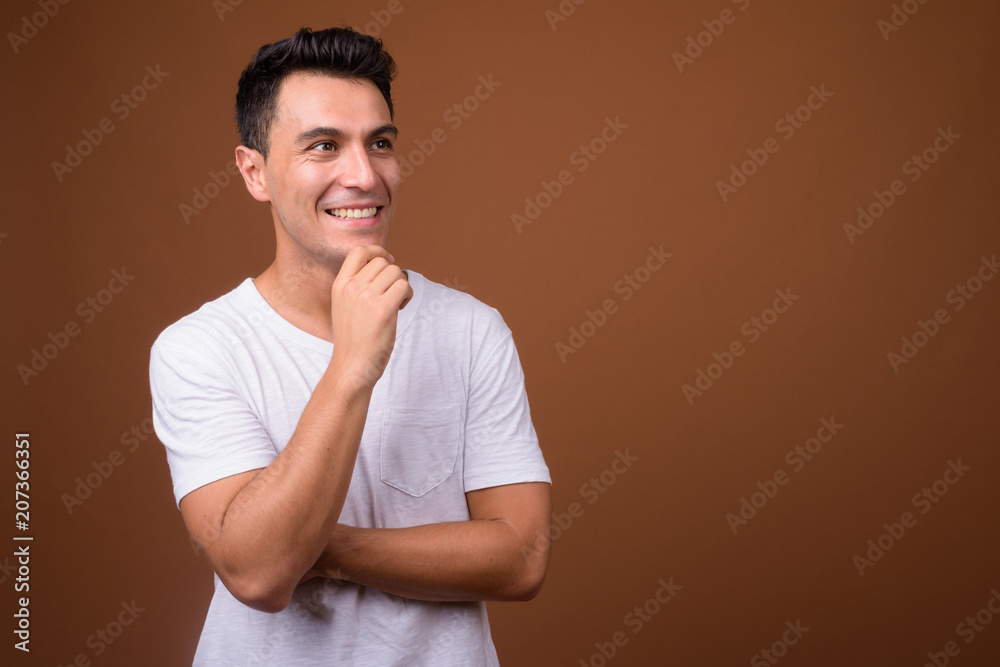 Young handsome Hispanic man against brown background Young handsome Hispanic man against brown background