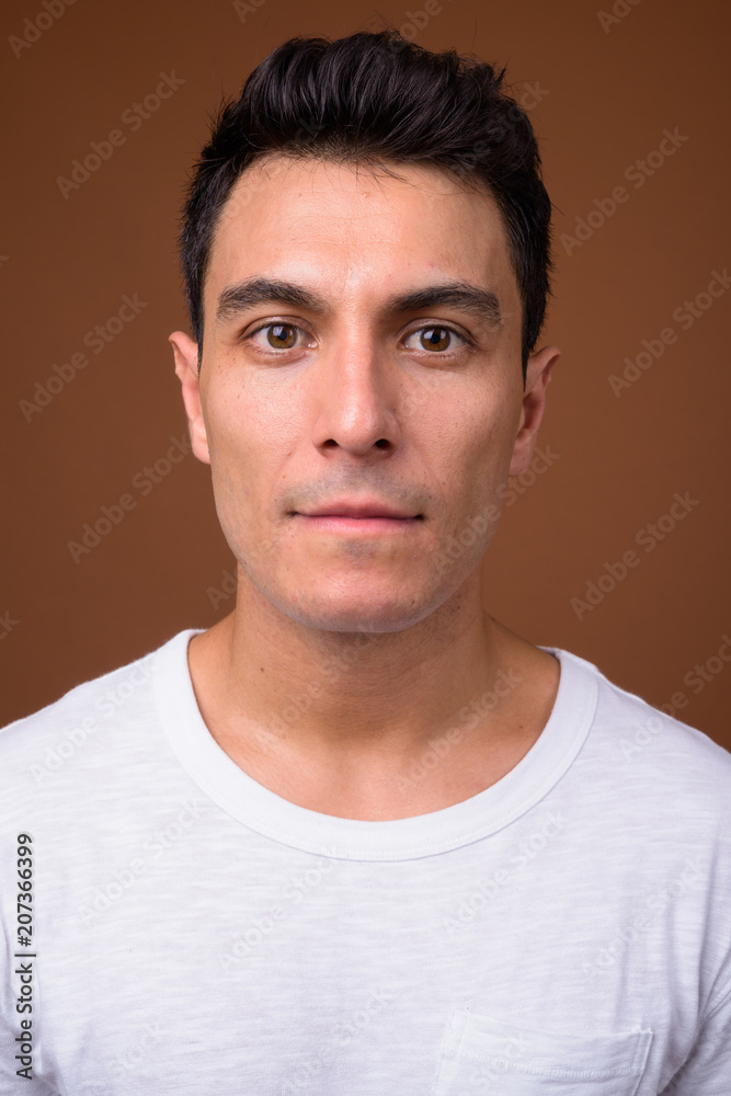 Young handsome Hispanic man against brown background Young handsome Hispanic man against brown background