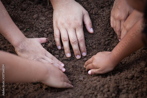 Children and parent helping prepare soil for planting together with unity and fun