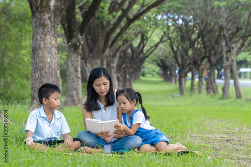 Asian family, mother, son and daughter doing reading activities at the park. © kokotewan