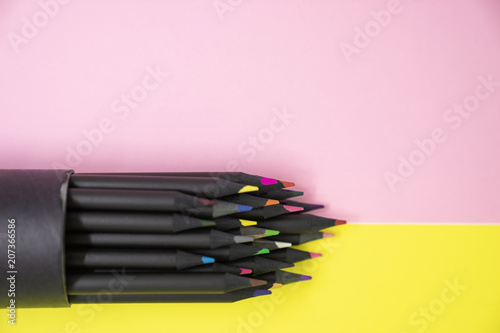 selective focus of group of black colourful pencil on bright yellow and pink background with copy space