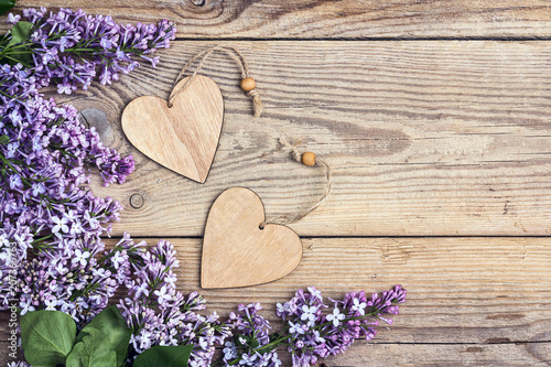 Lilac flowers with decorative hearts on old wooden background. Copy space.