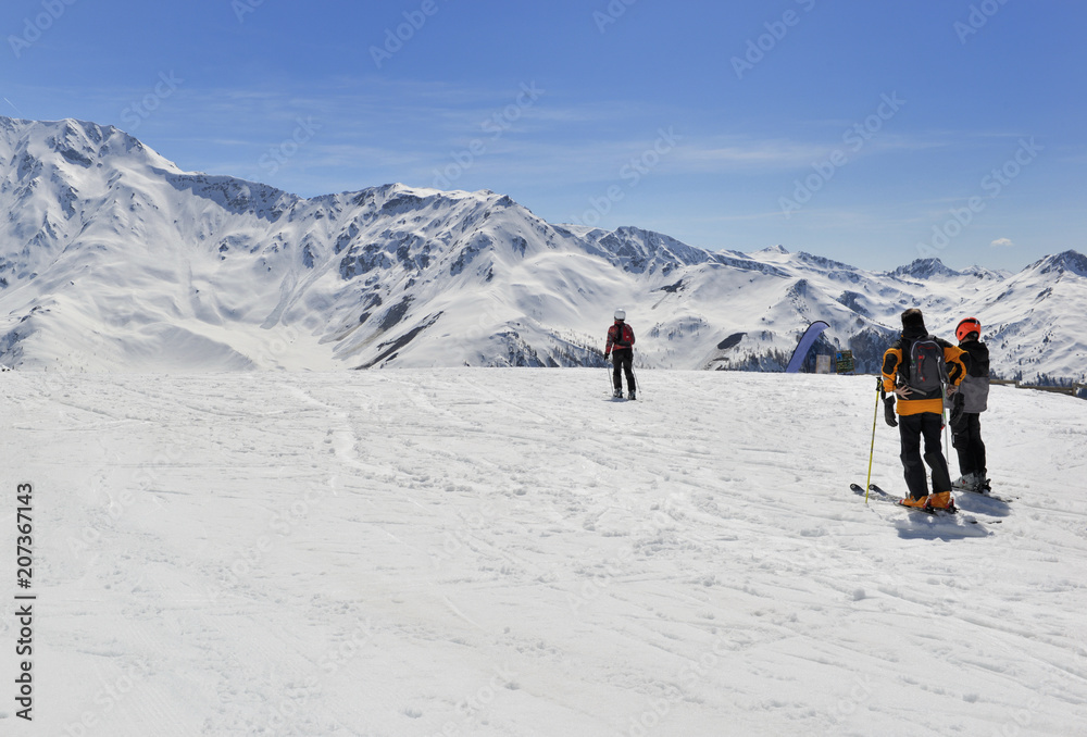 skiers on slopes in snowy alpine mountains 
