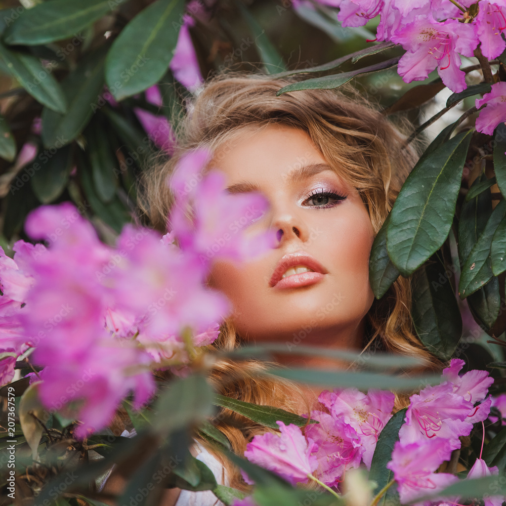 Portrait of a girl in a blooming garden. A bush of flowers is rhododendron pink. Beautiful hair and makeup. Portrait of a girl in a blooming garden. A bush of flowers is rhododendron pink. Beautiful hair and makeup.