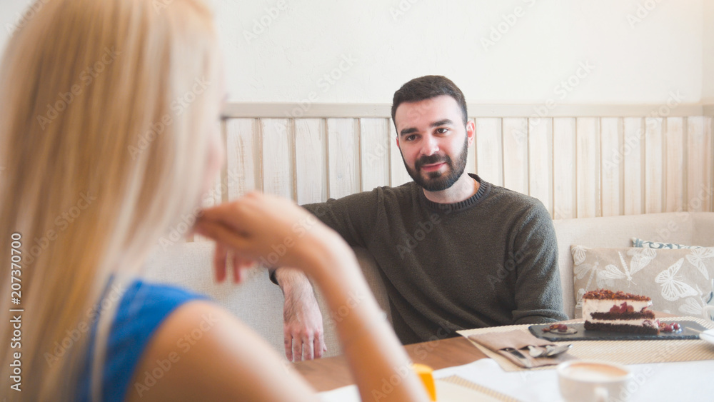 Obraz premium Young beard man and blonde girl have fun in a cafe