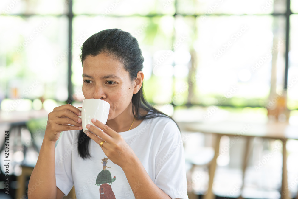 Asian girl is sitting to drink coffee at a coffee shop Asian girl is sitting to drink coffee at a coffee shop