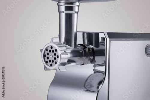 household electric meat grinder with nozzle on light grey background, close-up. kitchen appliances