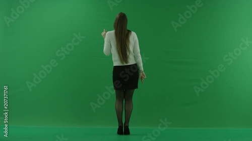 the girl stands with her back to the camera and dances on green screen